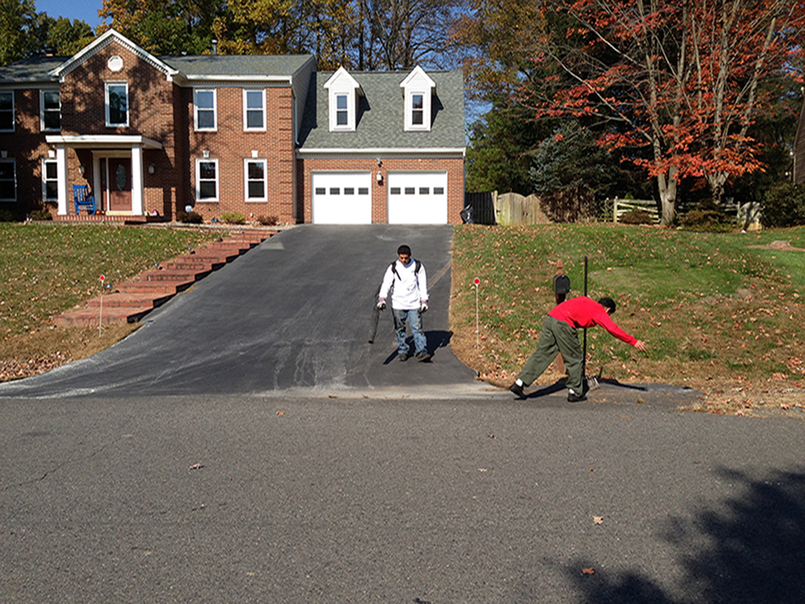 Two people clearing driveway of debris